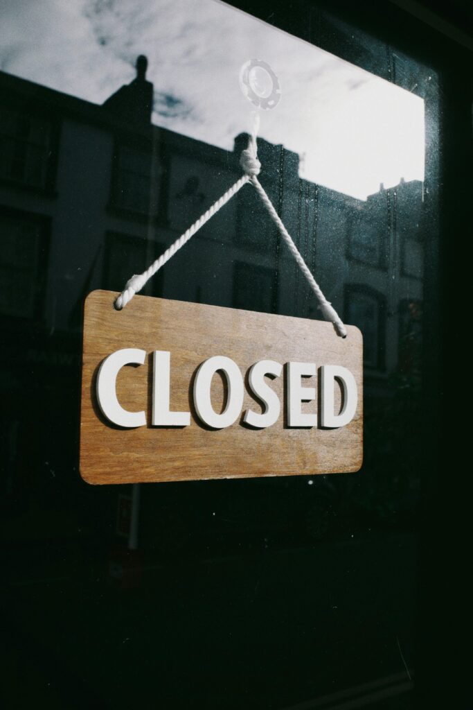 Simple wooden 'Closed' sign hanging on a shop window.