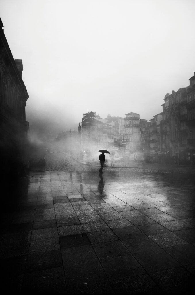 A lone figure with an umbrella in a foggy city, creating a moody, atmospheric scene.